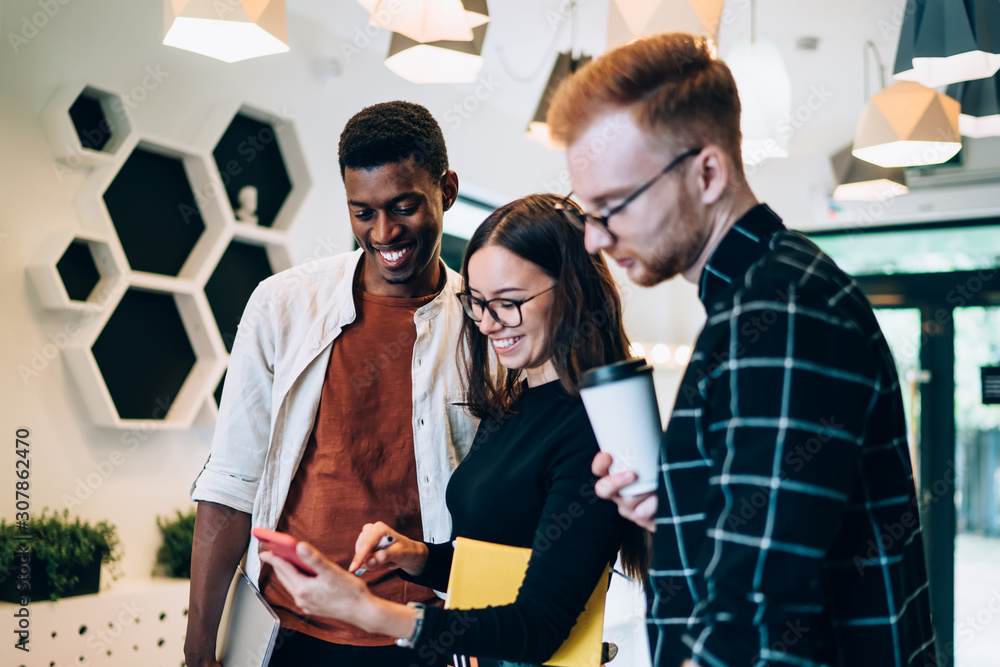 Poster cheerful diverse students discussing web information from university public page standing indoors an