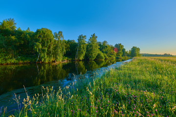 Peaceful rural summer european landscape with green trees and water