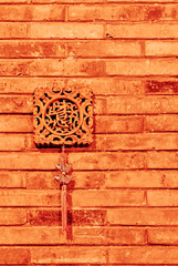 Traditional Chinese wooden decoration on a brick wall. Orange color background. Chinese carved wooden ornament with silk tassel and small shiny fish figures