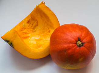 Ripe, orange pumpkin on a white table, cut for making porridge. Nearby is another whole.