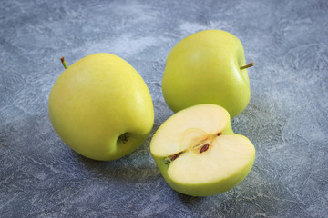 Fresh healthy green apples on decorative concrete background. Sliced apple for diet or detox nutrition. Closeup fruits on rusty background