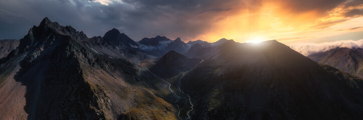 Panorama of high mountains at sunset. Dark mountain silhouettes, dramatic sky. - 307864838