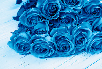 Blue color roses bouquet on wooden background.