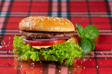  pork burger with cheese, tomatoes, cucumber, onions. bun with sesame seeds and bacon