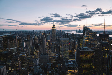 Aerial view of skyscrapers and towers in midtown skyline of Manhattan with evening sunset sky. Scenery cityscape of financial district with famous New York Landmark, illuminated Empire State Building