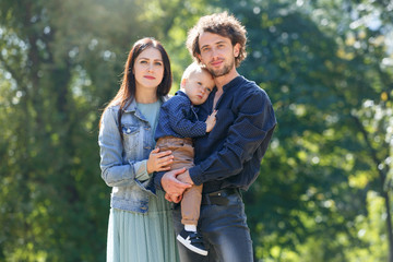 Fototapeta premium Family life. Portrait of parents and their son on the background of nature. Walk in park.