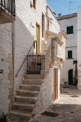 Obraz premium Narrow deserted street, stairs and white houses. Locorotondo, Italy.
