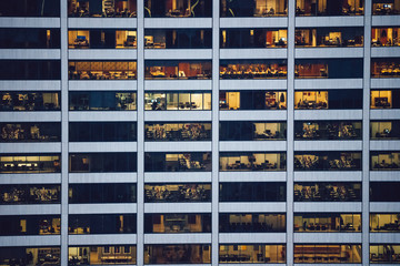 Aerial view of various high Manhattan skyscrapers buildings with lighted windows located in New York city at evening time. Night life of metropolis, offices and real estate. Downtown structures