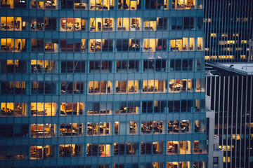 Aerial view of various high Manhattan skyscrapers buildings with lighted windows located in New York city at evening time. Night life of metropolis, offices and real estate. Downtown structures