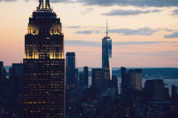 Cropped view of glowing skyscraper with beautiful sunset sky on background. Famous landmark Empire State Building with lighted facade, Scenery wallpaper