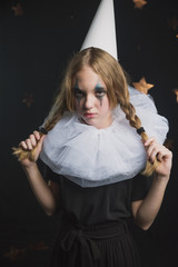 sad circus artist, clown girl in black and white outfit with a cap on her head