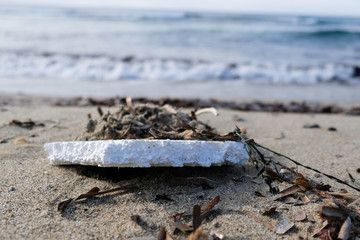 Polystyrene garbage on sandy sea shore on sunset golden light,pollution concept