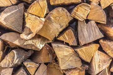 Wooden fire logs stacked up in the heap near the fence. Winter or Christmas background texture.