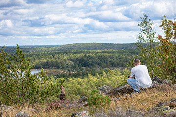 Fototapeta premium A man stands on a mountain, looks through binoculars, a beautiful sunny day