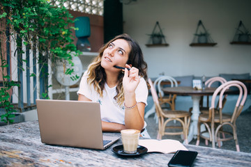 Young woman with laptop dreaming in cafe