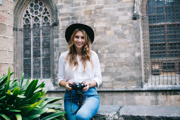 Cheerful woman with black hat and camera smiling and looking at camera