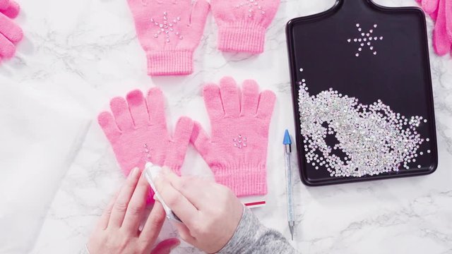 Flat lay. Rhinestone pink kids gloves with snowflake shapes.