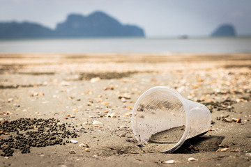 Plastic sink in a pile of sand on the beach.