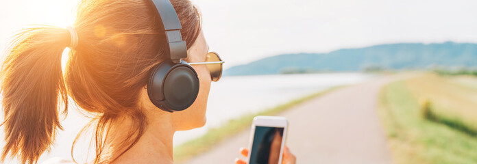 Young teenager girl starting jogging and listening to music using smartphone and wireless...