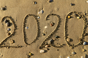 Children’s crooked figures 2020 in the sand with pebbles. Top view, horizontal, close-up....