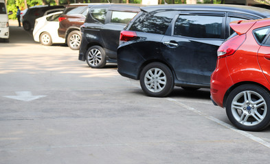 Closeup of rear, back side of red car with  other cars parking in outdoor parking area in sunny day.