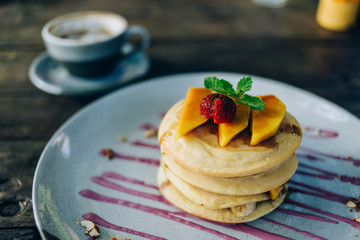 Delicious pancakes with fresh fruits and berries poured by sweet syrup