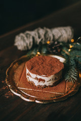 Christmas dessert - tiramisu on wooden background with Christmas tree and bokeh