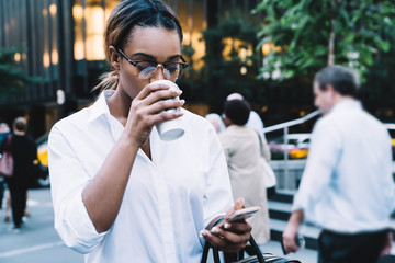 Focused business worker drinking coffee and checking mail in street