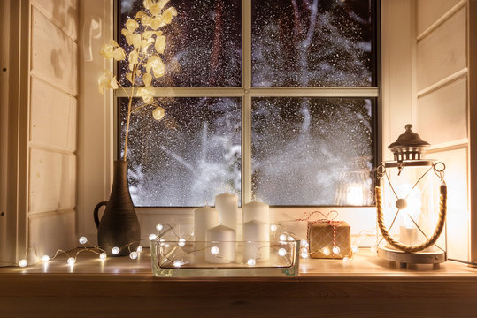 Beautiful burning candles and fairy lights on windowsill indoors