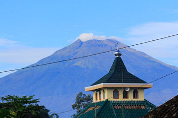 The peak of Mount Sumbing with a mosque dome as the foreground with a Javanese traditional...