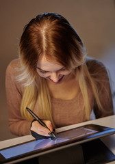 girl artist draws a digital pen on a professional tablet in her studio
