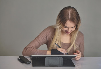 girl artist draws a digital pen on a professional tablet in her studio
