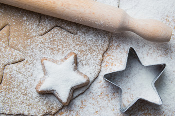 Cookies stars cut out of the dough preparation before baking along with prepared biscuit and rolling pin
