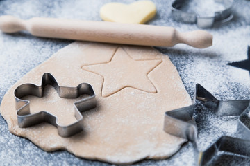 Process of making homemade christmas cookies with ingredients and cooking equipment on the table.