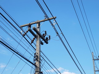 High-low voltage cables and cables on the pole On a bright blue sky background With copy space