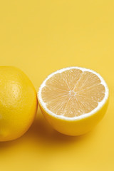 Lemon fruit slice and whole lemons on yellow background.