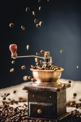 Coffee beans falling on wooden vintage coffee grinder. Grinding fragrant freshly roasted coffee