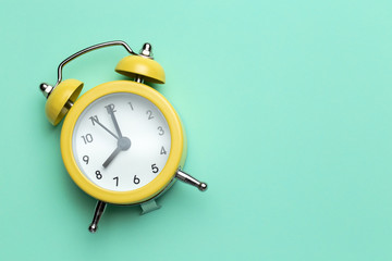 Yellow round alarm clock on the cyan background.