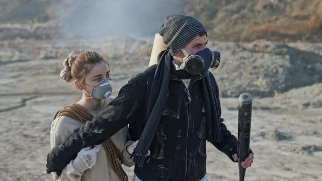 Couple of survivors in post apocalyptic wasteland are defending from the enemy with baseball bat.