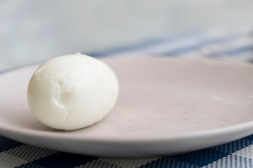 one boiled peeled egg does not lie flat on a plate. poverty, poverty, hunger