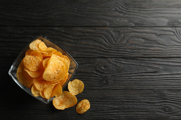 Potato chips in a place on wooden background, space for text. Top view