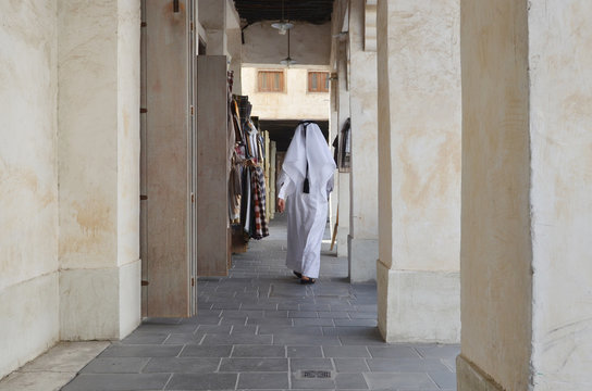 A Arabian man walking toward the end of the street at old soak of Doha.