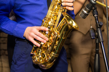Obraz premium Musical instruments, hands holding saxophone. Musician playing saxophone.