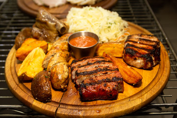 Barbecue ribs, and french fries with sauce on a wooden plate. Dish with a lot of fried meat.