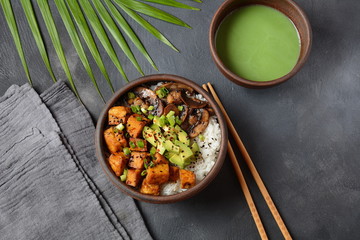 Sweet, spicy , crispy and fried Tofu in a bowl with terriayaki sauce, avocado,fried mushrooms, sesame seeds and rice. Served with green Matcha Tea. Healthy vegan food, gluten-free