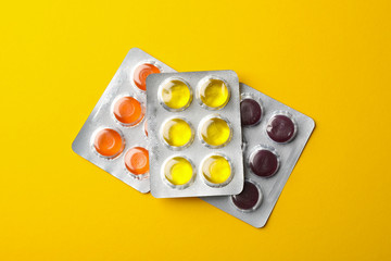 Medical candies in blister packs on yellow background, top view