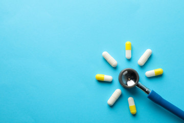Flat lay with pills and stethoscope on blue background, top view and space for text