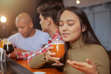 Young Asian woman enjoying drinking delicious beer at the pub with her friends