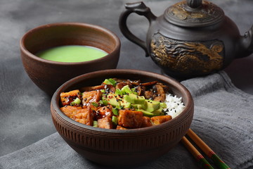 Sweet, spicy , crispy and fried Tofu in a bowl with terriayaki sauce, avocado,fried mushrooms, sesame seeds and rice. Served with green Matcha Tea. Healthy vegan food, gluten-free