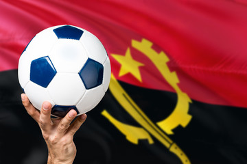 Naklejka premium Angola soccer concept. National team player hand holding soccer ball with country flag background. Copy space for text.